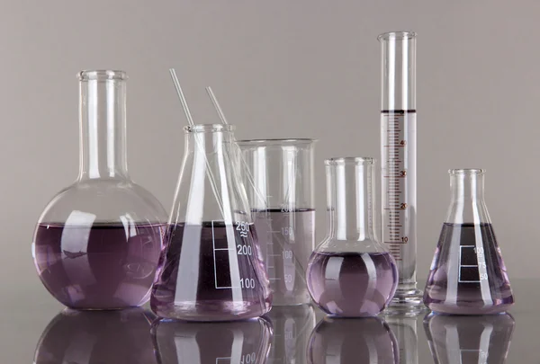 Test-tubes with light purple liquid on gray background — Stock Photo, Image