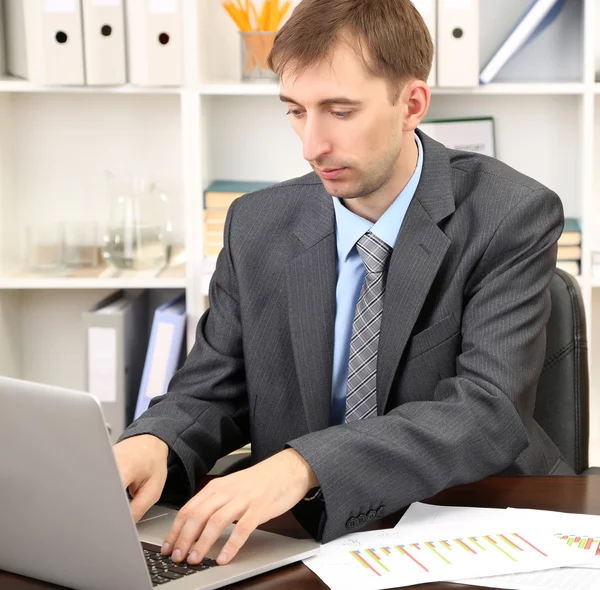 Jonge zakenman in kantoor op zijn werkplek — Stockfoto