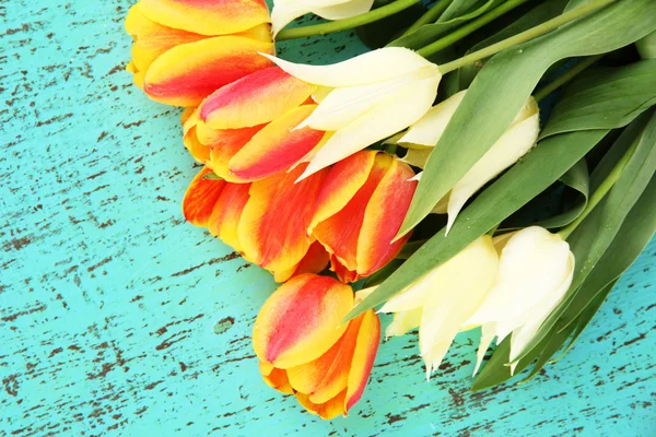 Schöne weiße und orangefarbene Tulpen auf farbigem Holzhintergrund — Stockfoto