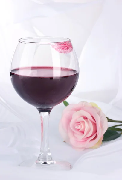 Sklenka vína s potiskem rtěnka na pozadí bílé tkaniny — Stock fotografie