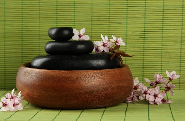 Piedras de spa y flores sobre fondo de bambú —  Fotos de Stock