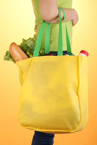 Mädchen mit Einkaufstasche auf orangefarbenem Hintergrund — Stockfoto