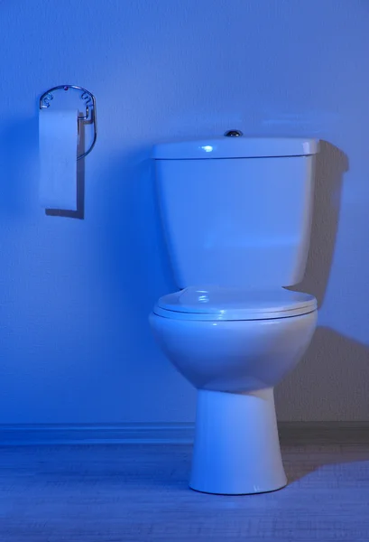 Toalete e papel higiênico em um banheiro com luz azul — Fotografia de Stock