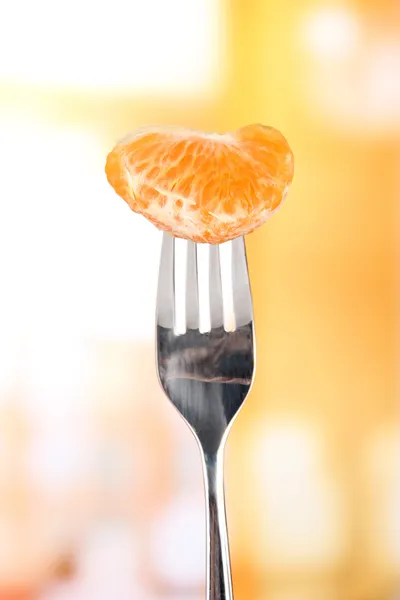 Fatia de tangerina em garfo, em fundo brilhante — Fotografia de Stock