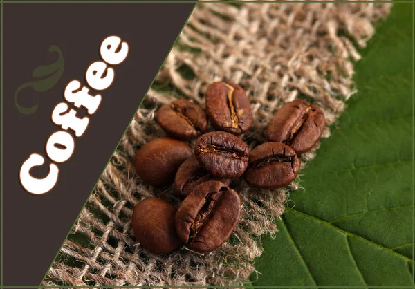 Kávové zrna v žíně na zelené listy close-up — Stock fotografie