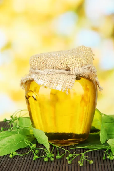 Pot met honing met bloemen van kalk, op kleur bamboe mat op lichte achtergrond — Stockfoto