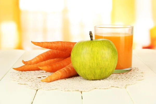 Un mucchio di carote e mela verde, vetro di succo, su tavolo di legno a colori su sfondo brillante — Foto Stock