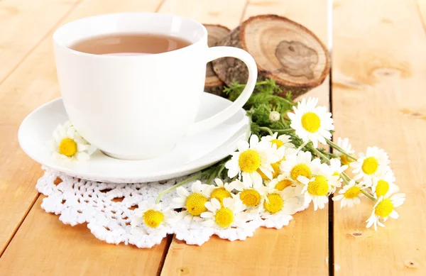 Cup of chamomile tea and chamomile on wooden table — Stock Photo, Image