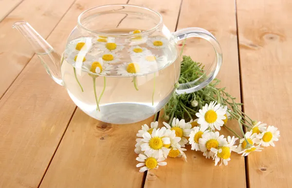 Glass teapot with chamomile on wooden table — Stock Photo, Image