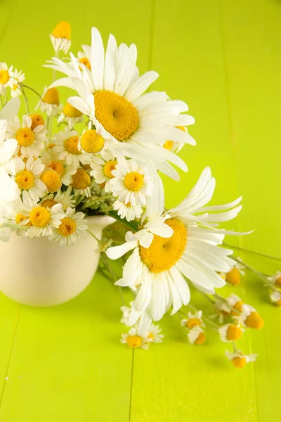 Beautiful bouquet chamomiles in pitcher on wooden table close-up — Stock Photo, Image