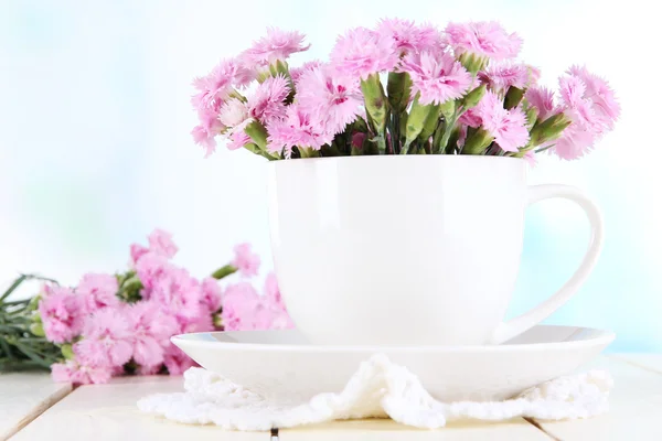 Viele kleine rosa Nelken in Tasse auf Holztisch auf Fensterhintergrund — Stockfoto