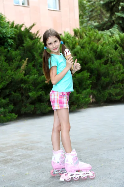 小さな女の子がローラー スケート公園でおいしいアイスクリームを食べる — ストック写真