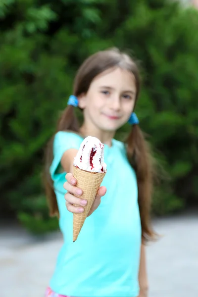 Niña patina comiendo sabroso helado en el fondo del parque —  Fotos de Stock