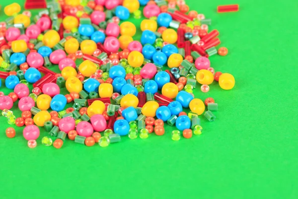 Different colorful beads on green background — Stock Photo, Image