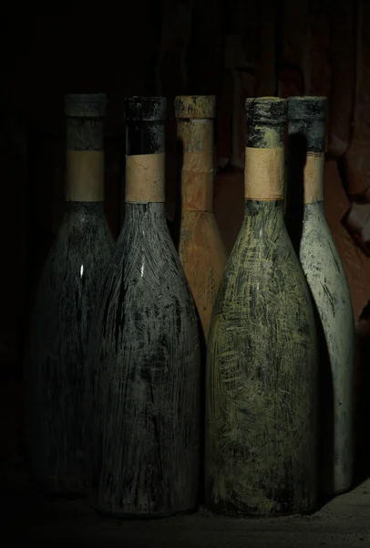 Garrafas velhas de vinho na adega velha, no fundo escuro — Fotografia de Stock