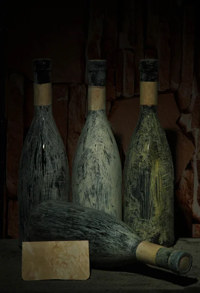 Viejas botellas de vino en bodega vieja, sobre fondo oscuro — Foto de Stock