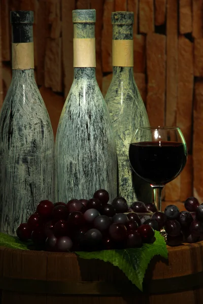 Композиція зі старими пляшками вина та келихами в старому підвалі, на темному тлі — стокове фото
