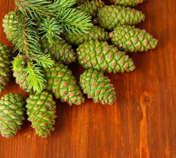 Coni verdi e abete su sfondo di legno — Foto Stock