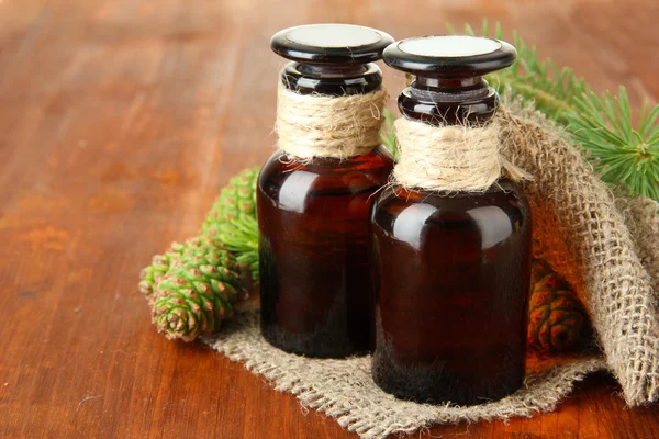 Flessen van fir tree olie en groen kegels op houten achtergrond — Stockfoto