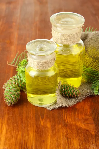 Botellas de aceite de abeto y conos verdes sobre fondo de madera —  Fotos de Stock