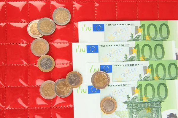 Notas de euro e cêntimos de euro sobre fundo vermelho — Fotografia de Stock