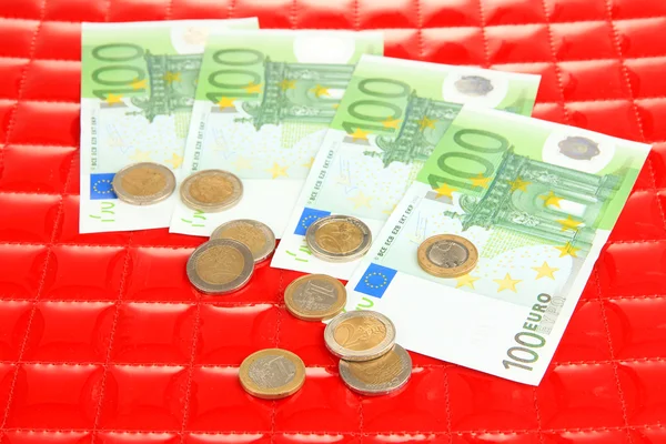 Euro banknotes and euro cents on red background — Stock Photo, Image