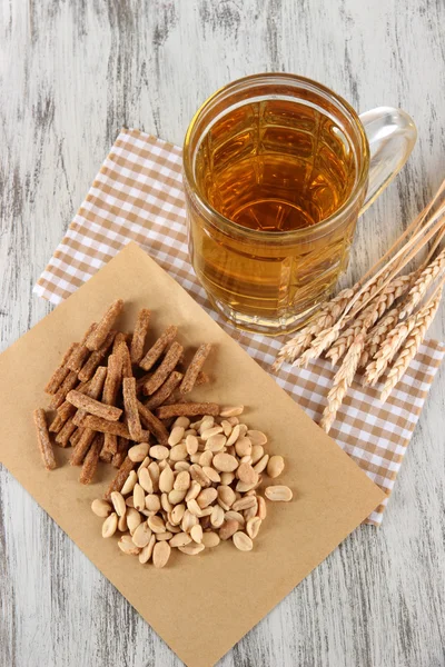 Beer in glass crunches, and nuts on napkin on wooden table — Stock Photo, Image