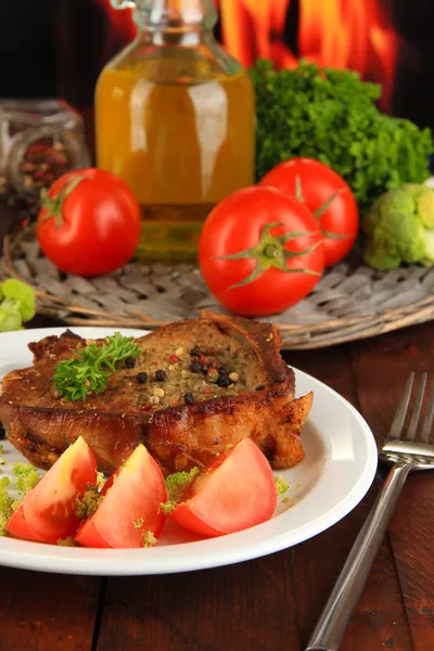 Stück gebratenes Fleisch auf Teller auf Holztisch auf Feuer Hintergrund — Stockfoto