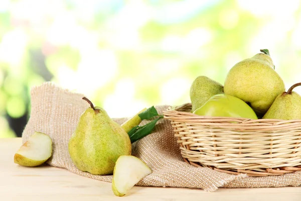 Pears in basket on burlap on wooden table on nature background — Stock Photo, Image