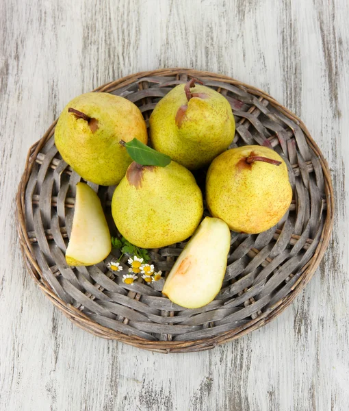 Pears on braided tray on wooden table — Stock Photo, Image