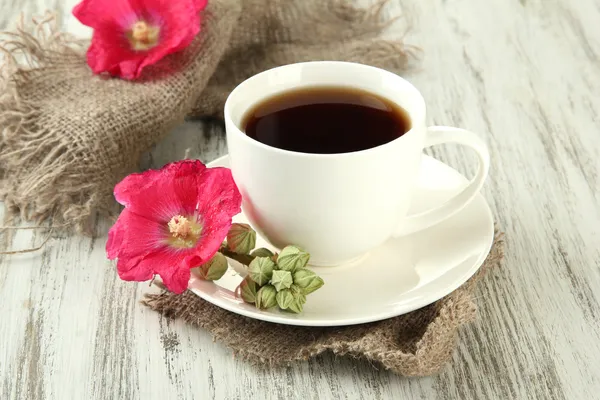 Kopje koffie en roze kaasjeskruid bloemen op houten achtergrond — Stockfoto