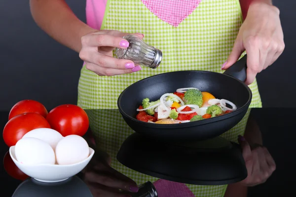 Mains faisant cuire le ragout de légumes dans une casserole sur fond gris — Photo