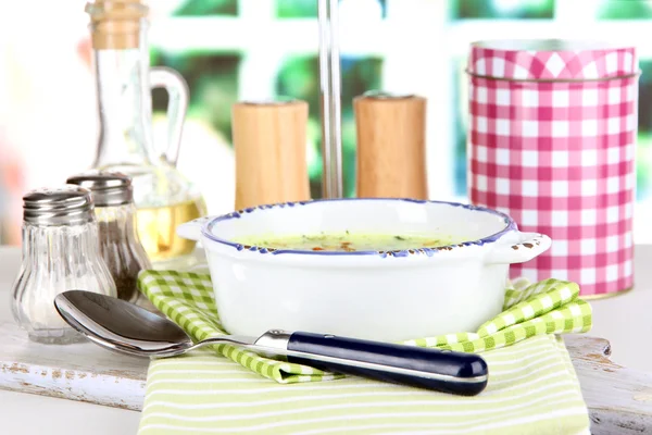 Soupe dans une assiette sur une serviette sur une planche en bois sur fond de fenêtre — Photo