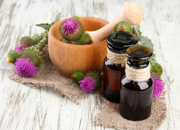 Medizinflaschen und Mörser mit Distelblumen auf Holzgrund — Stockfoto