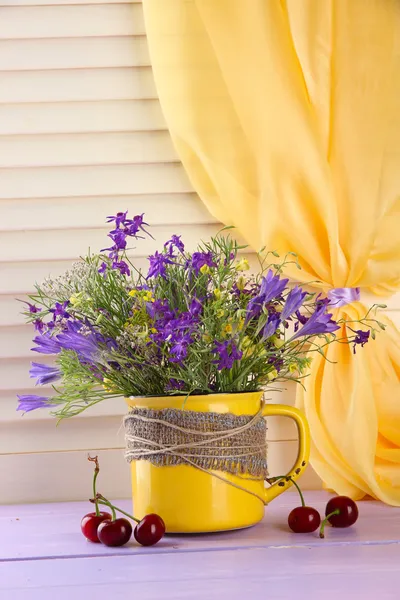 Mooi boeket van wilde bloemen in cup en bessen op houten tafel — Stockfoto