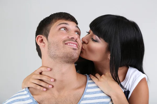 Schönes verliebtes Paar küsst auf grauem Hintergrund — Stockfoto
