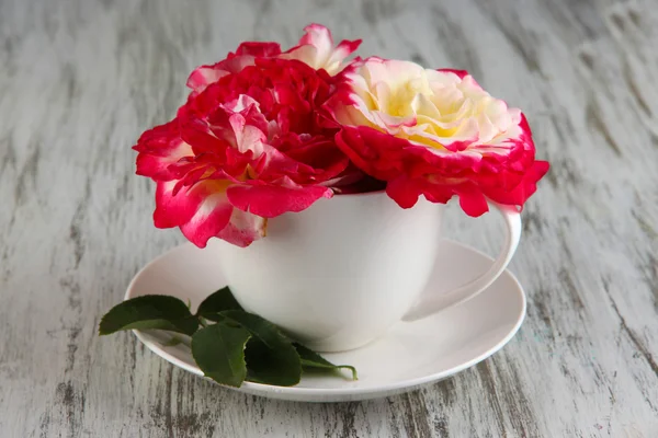 Rosen in Tasse auf Holzgrund — Stockfoto
