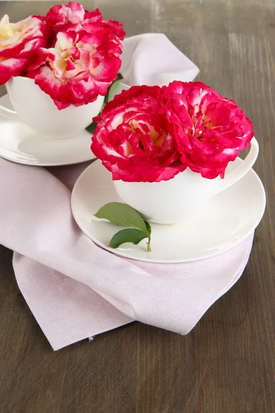 Roses en tasses sur serviette sur fond en bois — Photo