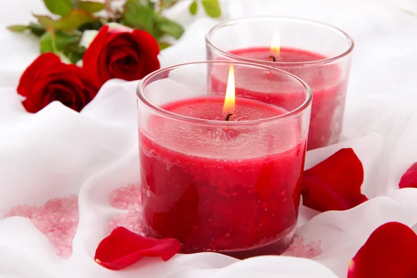 Beautiful candles with flowers on white cloth, close up — Stock Photo, Image