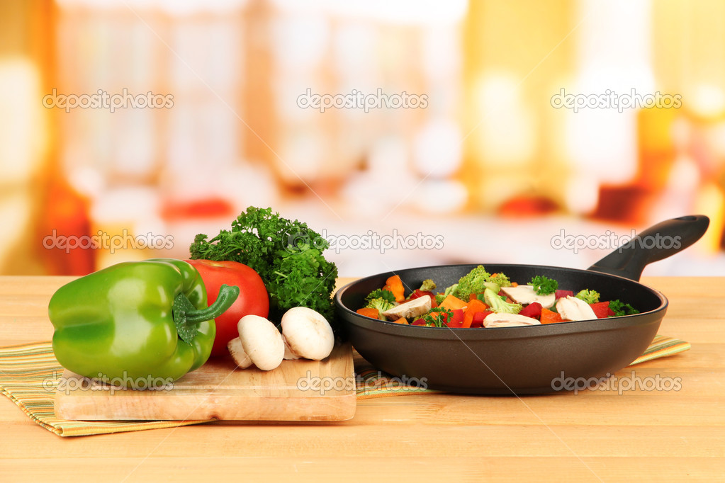 Vegetable ragout in pan, on wooden table on bright background