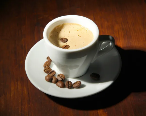 Šálek kávy zrnkové kávy na dřevěné pozadí — Stock fotografie