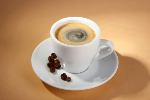 Kopje koffie met koffiebonen op beige achtergrond — Stockfoto