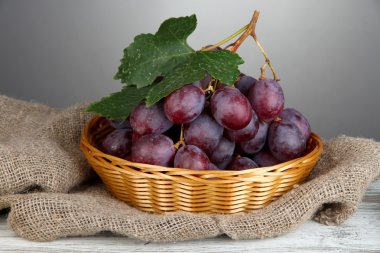 hasır sepet tabloda gri arka plan üzerinde olgunlaşmış lezzetli üzüm