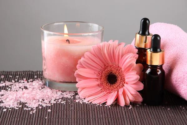 Beautiful pink candle with flower and towel on bamboo mat — Stock Photo, Image