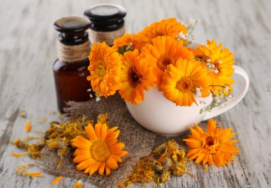 Medicine bottles and calendula flowers on wooden background clipart