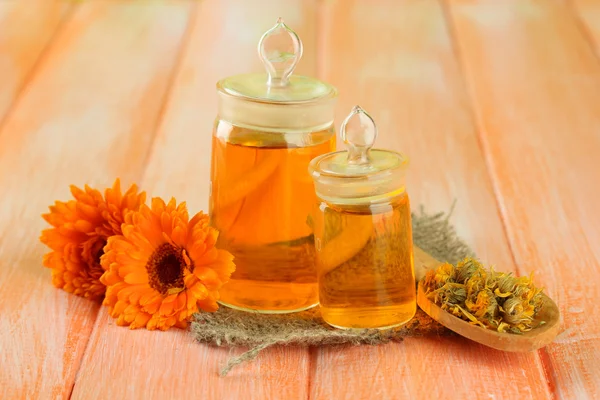 Medicine bottles and calendula flowers on wooden background — Stock Photo, Image