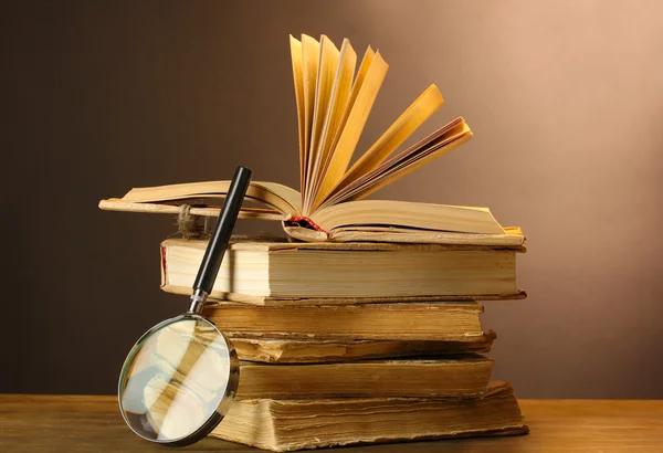 Magnifying glass and books on table — Stock Photo, Image