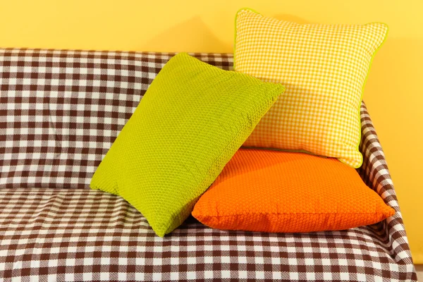 Oreillers colorés sur canapé sur fond jaune — Photo