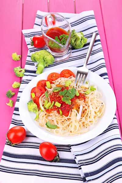 Leckere Spaghetti mit Sauce und Gemüse auf Teller auf Holztisch in Großaufnahme — Stockfoto