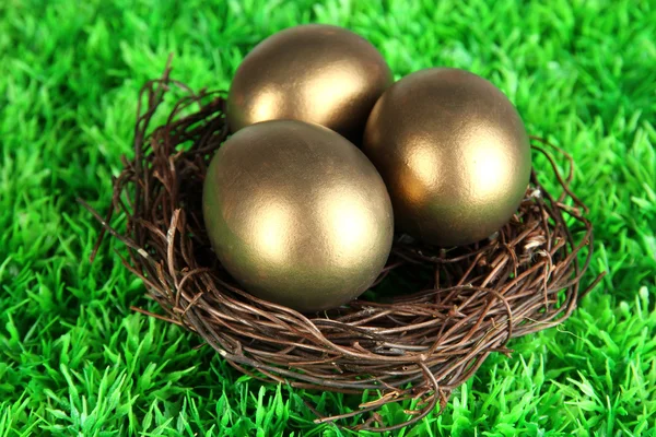Три золотых яйца на траве — стоковое фото